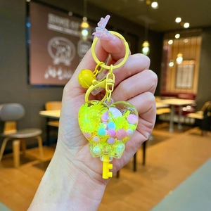 Close-up of heart-shaped liquid quicksand bottle keychain with colorful beads and bell
