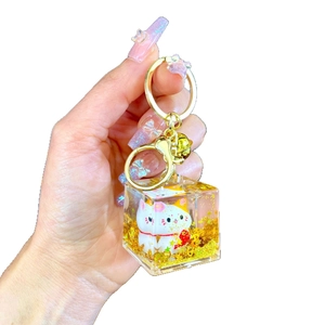 Lucky cat keychain with golden sequins and transparent resin square charm in hand