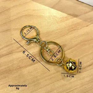 Detail of gold metal keychain with lobster clasp, ring and bell on wood background