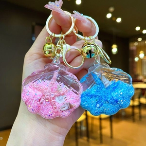 Detail of pink and blue seashell liquid glitter keychains with golden bells and charms