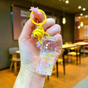 Macro detail of yellow drifting bottle keychain with flowing glitters and small bell