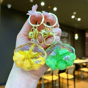 Detail of colorful shell keychains with ocean sand and mini starfish charms in hand