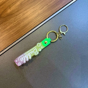Detail of gradient silicone strap keychain with gold clasp and Bubble lettering