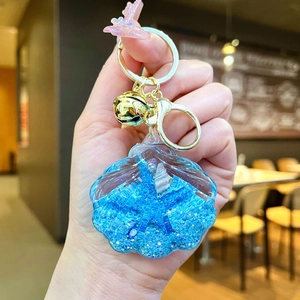 Detail of shell-shaped keychain with blue floating liquid and glitter elements