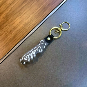 Close-up of translucent grey acrylic keychain with Bubble script and golden metal ring
