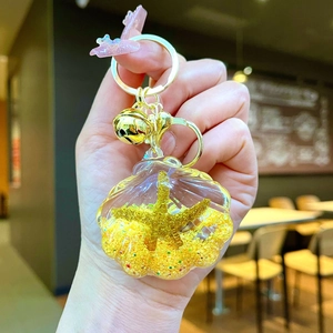 Detail of shell keychain with yellow sand and golden starfish in a hand-held macro shot