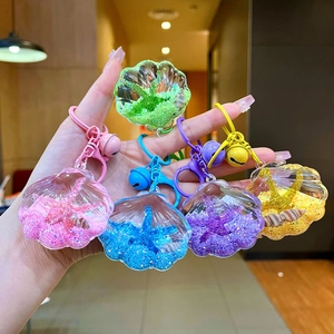 Close-up of colorful seashell oil-filled keychains with glitter, starfish, and bells