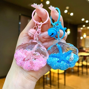 Close-up of ocean shell acrylic keychains with liquid sand and small metal bells