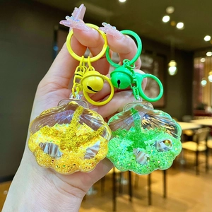 Close-up of shell-shaped liquid sand keychains with yellow and green acrylic finishes