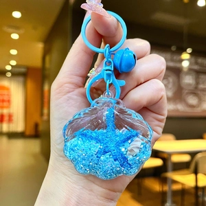 Macro detail of acrylic sea shell keychain with blue glitter oil and lobster clasp