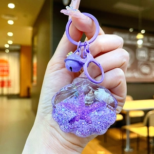 Close-up of purple shell acrylic keychain with glitter, seashells, and bell detail