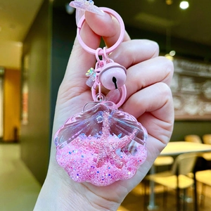 Detailed shot of a pink seashell oil keychain with floating sand and starfish charm