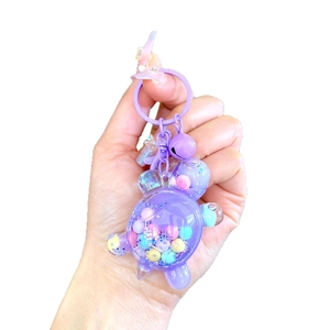 Cute purple bear-shaped keychain with colorful beads and glitter displayed in hand