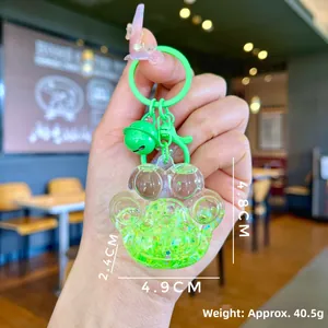 Detailed view of green cat paw quicksand keychain with glitter and small bell