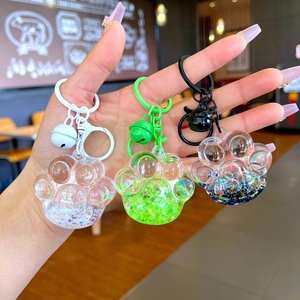 Handheld liquid quicksand cat paw keychains in white, green, and black colors