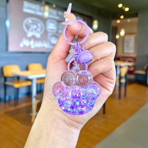 Detail of purple cat paw liquid glitter keychain with bell and star sequins in hand