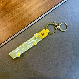 Makroaufnahme von gelbem Silikon-Schlüsselanhänger mit Happy Moments Druck und Goldring