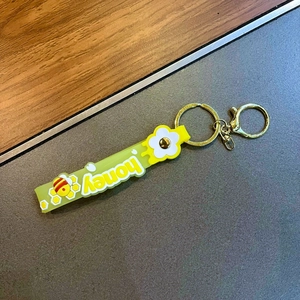 Detail of yellow silicone honey keychain featuring 3D bee and flower designs with gold clasp