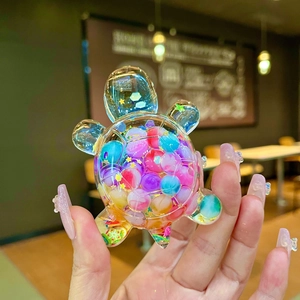 Handheld variant of macaron turtle ornament with colorful fruit beads in a clear shell