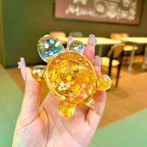 Turtle shaped liquid quicksand toy in transparent acrylic with golden glitter petals