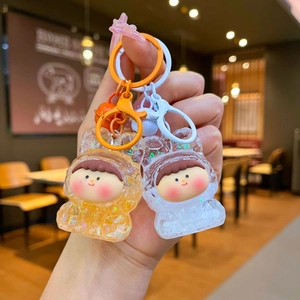 Glittering acrylic liquid keychain with cartoon character held against cafe background
