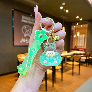 Close-up of Sakura theme keychain with green resin rabbit, glitter and silicone wrist strap