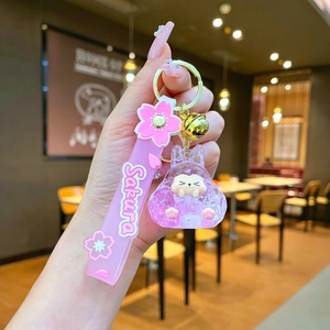 Detail of pink Sakura pet keychain with liquid quicksand, resin animal, and gold bell