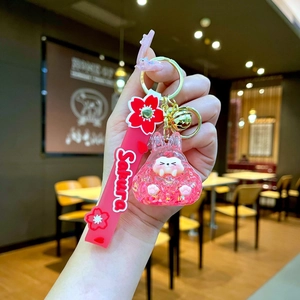 Detail of pink resin bunny keychain with gold bell and Sakura print red wrist strap