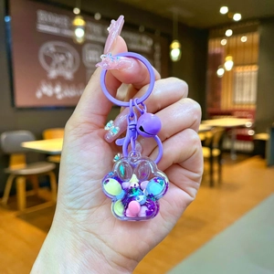 Gros plan d'un porte-clés patte de chat violet avec paillettes brillantes et clochette