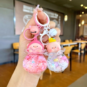 Detail of pink and white peach pig acrylic liquid glitter keychains held in hand