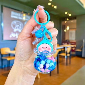 Detailed close-up of a pink pig keychain with blue glitter liquid and charms