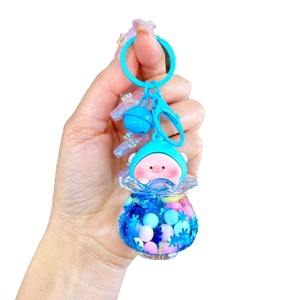 Luminous floating pig keychain with blue liquid glitter and bell on white background