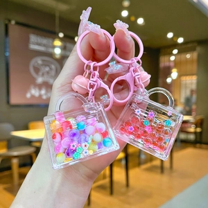 Detail of luminous liquid bead handbags keychains with pink bells and floral sequins
