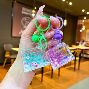 Close-up of creative liquid handbags keychains with glitter, flowers and small metal bells