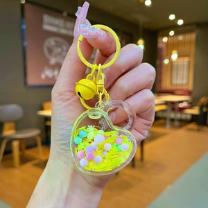 Macro detail of a bright yellow heart-shaped acrylic keychain with colorful beads inside