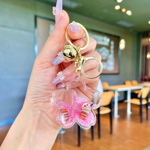 Detail of pink sakura bottle keychain with floating starfish, shell, and gold bell charm