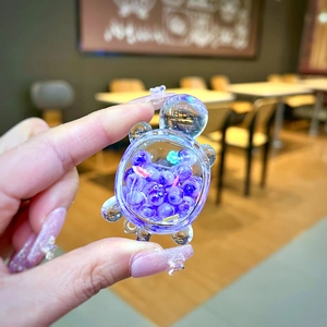 Close-up of a creative turtle resin charm filled with purple beads and glitter details