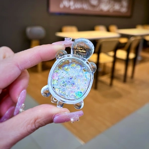 Macro detail of a transparent resin turtle pendant with iridescent glitter ball filling