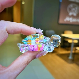 Macro shot of a tiny transparent resin turtle figurine filled with colorful beads