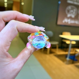 Macro shot of a colorful mini turtle resin charm with vibrant beads held by fingers