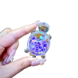 Luminous turtle resin charm with purple glitter beads and green flower inside