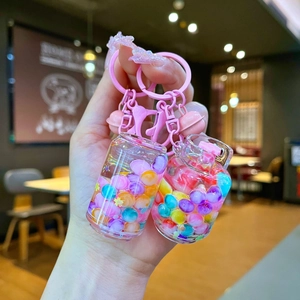 Close-up of pink liquid quicksand keychain with colorful beads and bell details