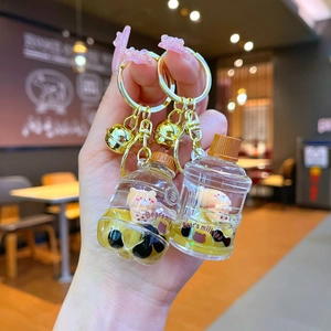 Macro view of bubble tea bear keychain with floating liquid and golden bell accessories