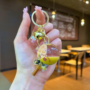 Detail of creative milk tea keychain with floating bear liquid and golden bell charm