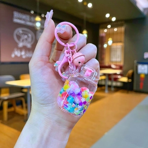 Detailed close-up of a pink floating glitter bottle keychain with colorful beads and bell