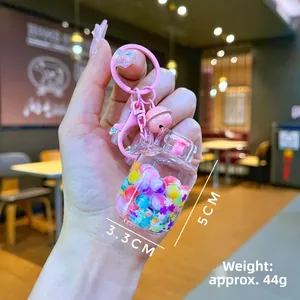 Close-up of pink liquid-filled keychain with colorful beads, stars, and small bell