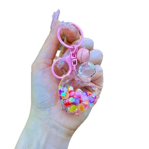 Cute heart-shaped liquid keychain with colorful beads and a pink bell on a metal hook