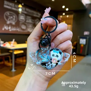 Détail d'un porte-clés panda en forme de cœur ailé avec flocons bleus, donut et cloche noire
