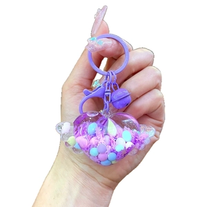 Porte-clés cœur violet avec ailes et perles de macaron dans du sable mouvant
