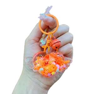 Cute glowing heart with wings keychain in orange resin, held by hand on white background
